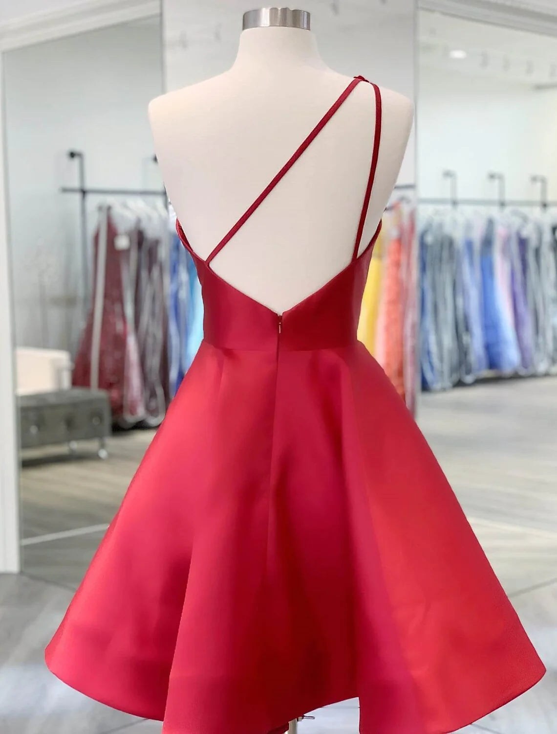 Back view of a model in a light blue one-shoulder satin mini dress, showcasing the backless design.