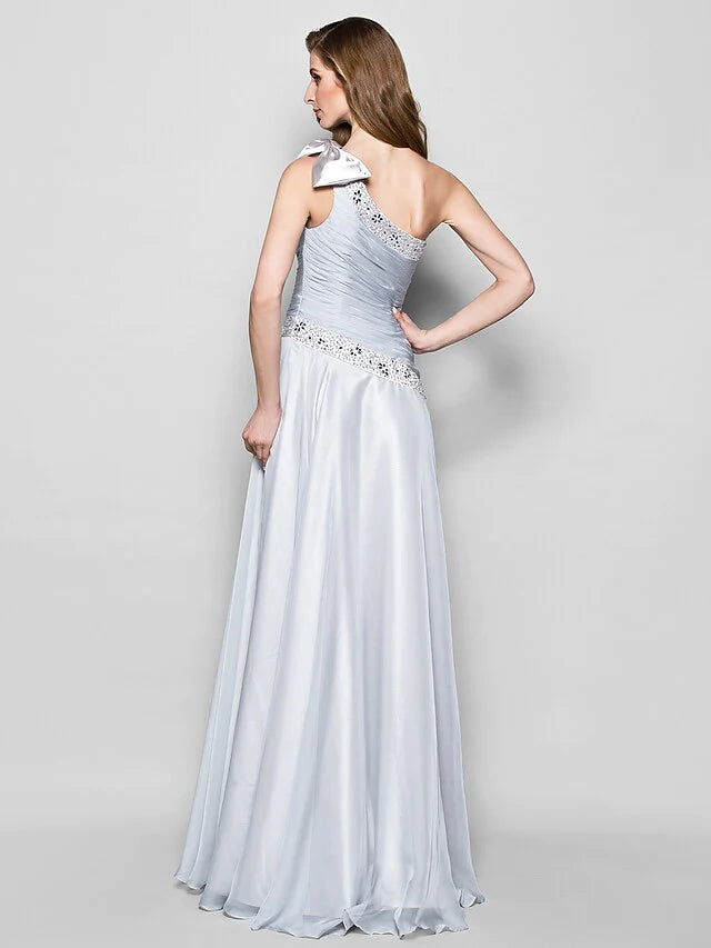 Back view of an A-line one-shoulder chiffon gown with a flowing skirt.