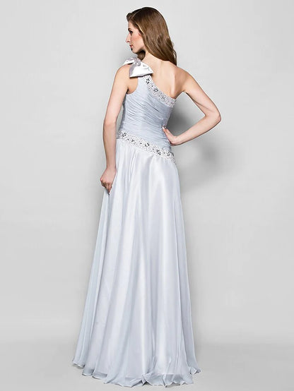 Back view of an A-line one-shoulder chiffon gown with a flowing skirt.