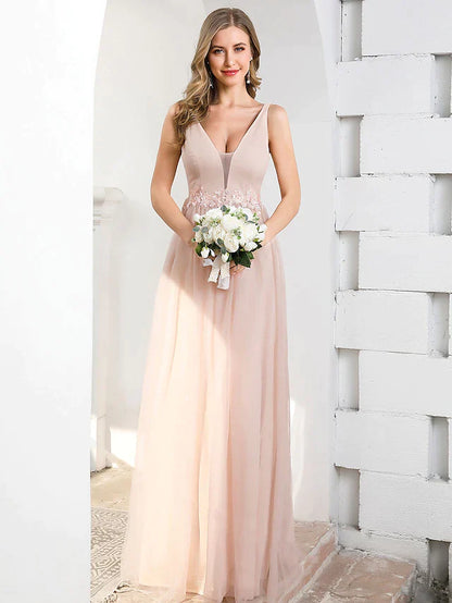 Woman wearing an A-line plunging neck tulle bridesmaid dress with appliques, front view.