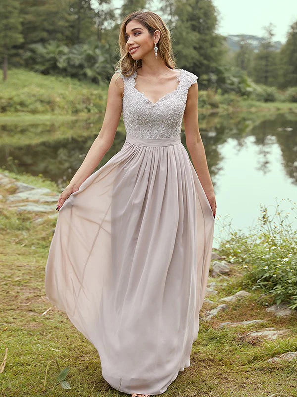 Woman wearing an elegant A-line chiffon bridesmaid dress with short sleeves and applique.