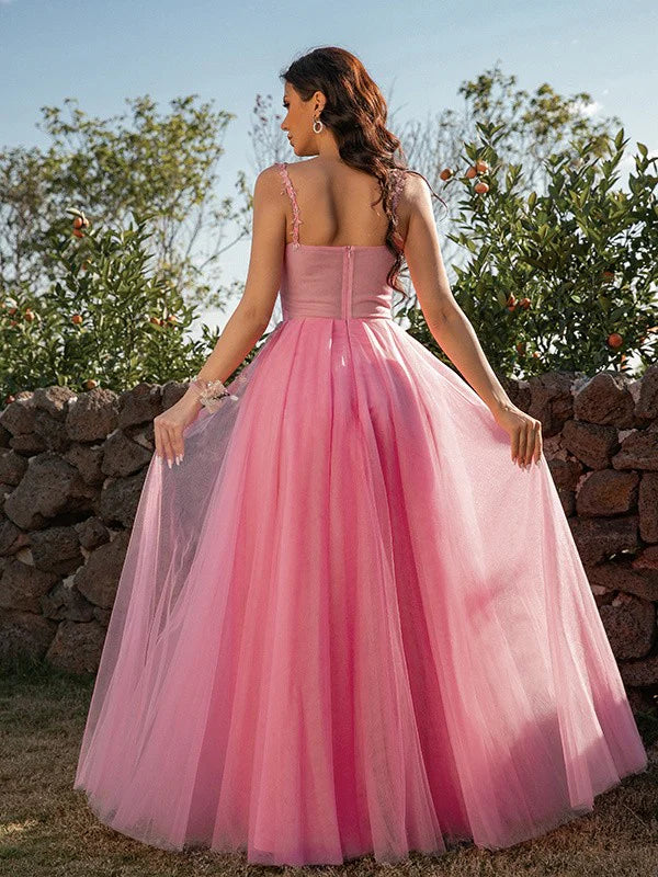 Back view of a woman in an A-line princess tulle applique floor-length formal dress.