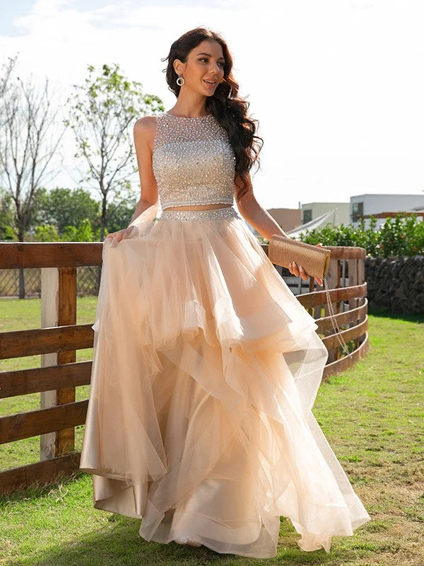 Model wearing an elegant A-Line two-piece prom dress with a beaded scoop neck and tulle skirt.