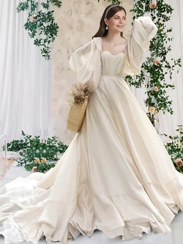Bride wearing an elegant A-Line scoop neck long sleeve chiffon wedding dress with pleats and chapel train.