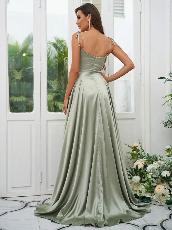 A woman in a light-colored A-line bridesmaid dress with ruffles and spaghetti straps, viewed from the back.