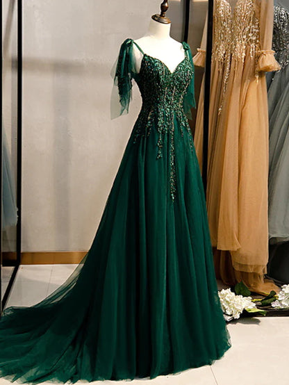 Woman wearing an elegant A-line formal evening dress with spaghetti straps and beading, front view.