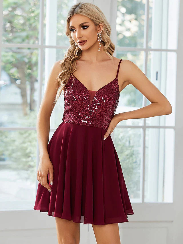 Model wearing an elegant A-line spaghetti strap short dress with sequins and pleats.