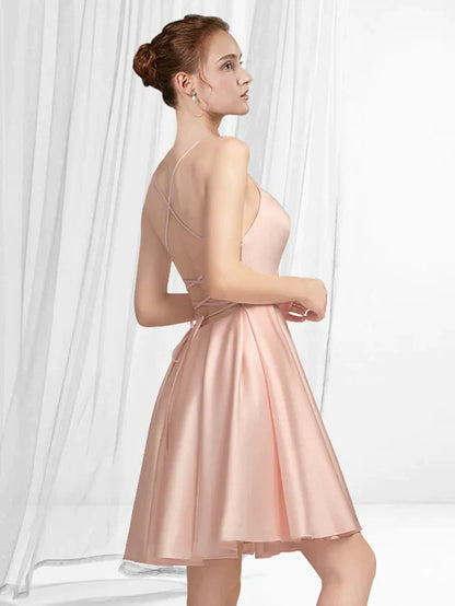 Woman posing in an A-line spaghetti strap mini satin dress with pleats, side view.