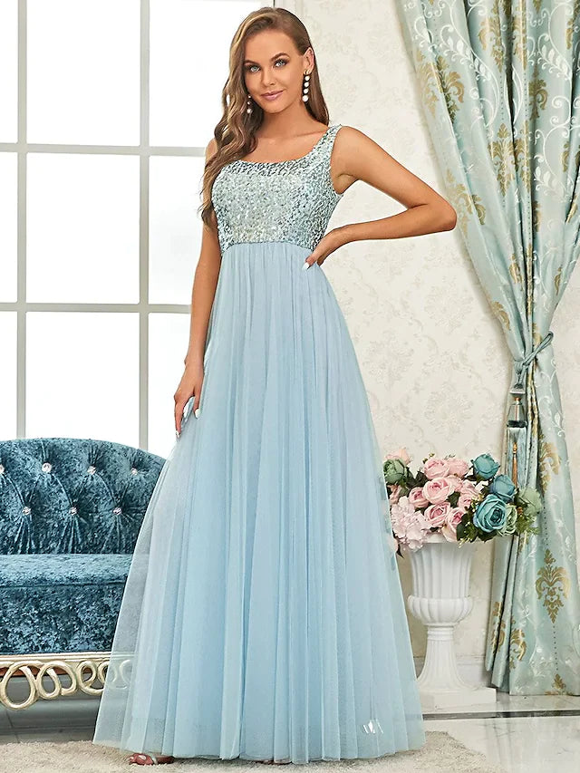 Woman wearing a light-colored A-line sequined tulle bridesmaid dress with spaghetti straps.