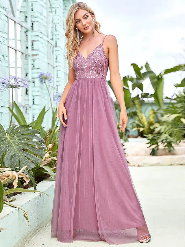 Model wearing a light-colored A-line spaghetti strap sequined tulle tiered floor-length bridesmaid dress.