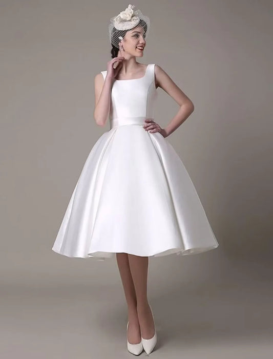 Model wearing an elegant A-line satin cocktail dress with a square neck and pleats.