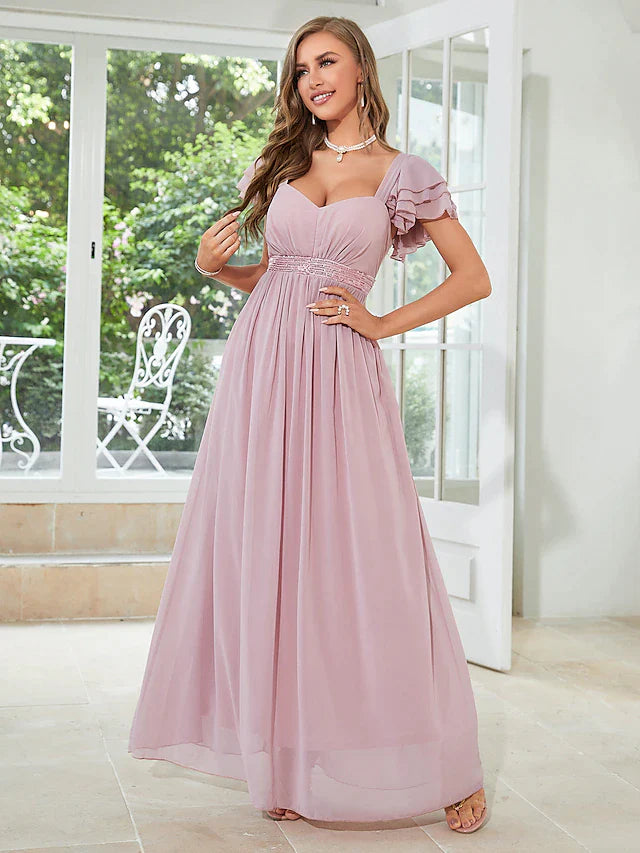 Woman posing in an elegant light blue A-line chiffon dress with square neck and short ruffled sleeves.