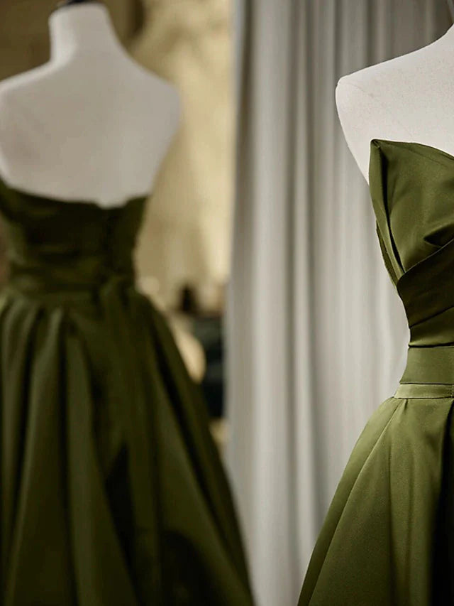 Side view of a woman in a pleated A-line strapless satin evening gown.