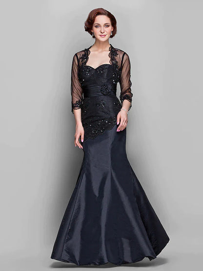 Woman wearing an elegant floor-length Mother of the Bride dress with a sweetheart neckline, long sleeves, and lace.