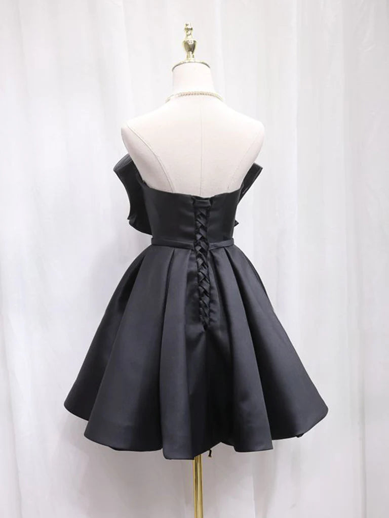 Close-up of black satin fabric and sweetheart neckline on a short dress.