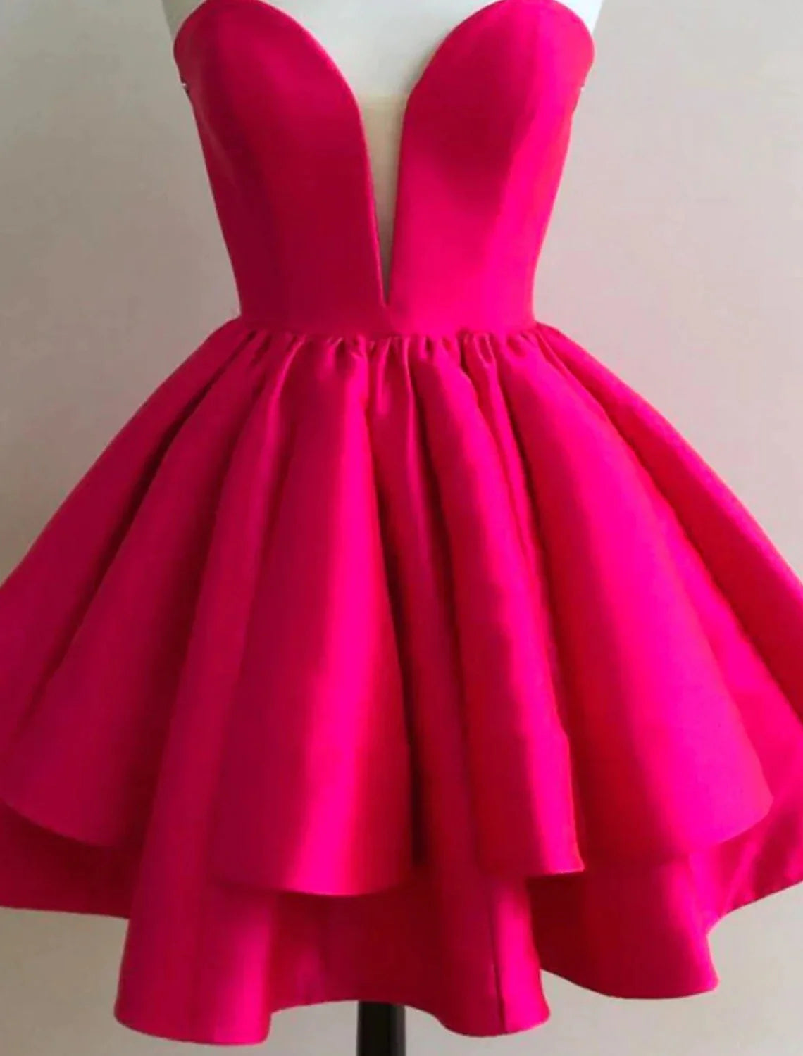 Back view of a woman in a pink A-line short satin dress, highlighting the backless design and ruffles.