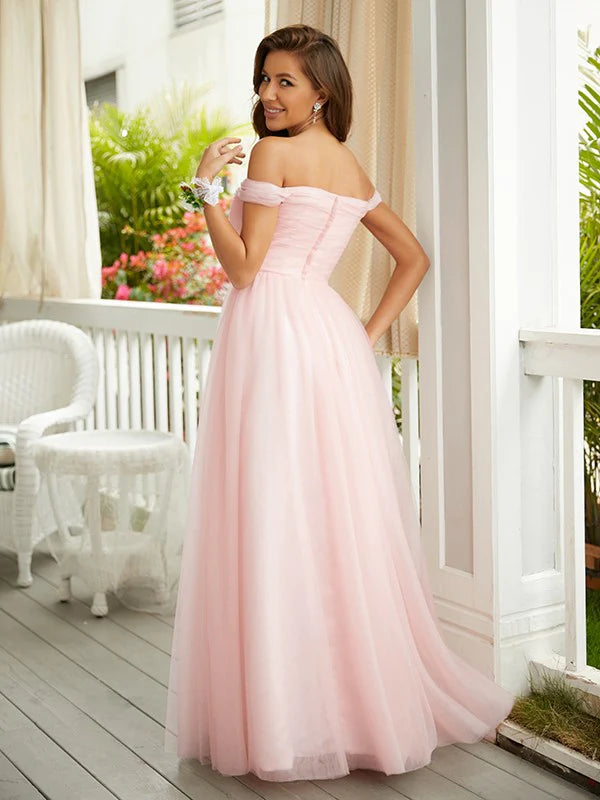 Woman in a light pink A-line off-shoulder tulle prom dress, posing from the side.