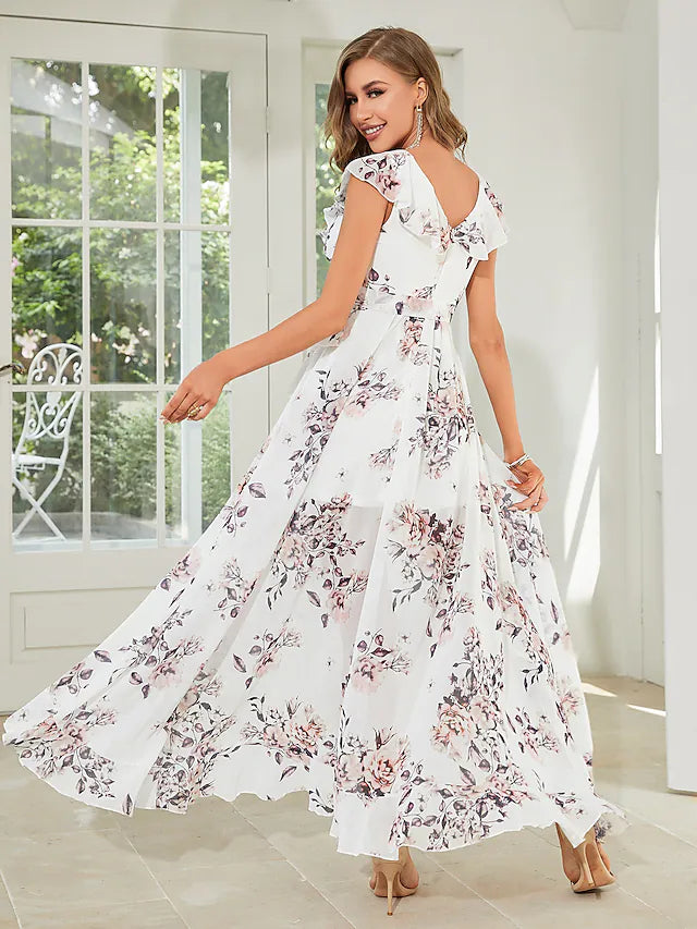 Side view of a woman in a floral A-line dress, showing the asymmetrical hem and delicate strappy details.