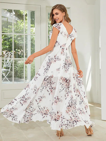 Side view of a woman in a floral A-line dress, showing the asymmetrical hem and delicate strappy details.