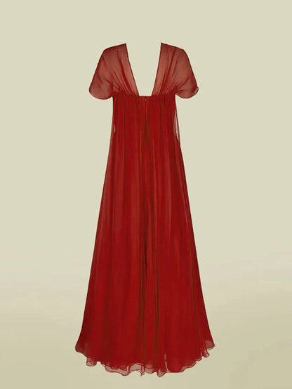 Model in an A-line V-neck chiffon dress, showing the back and flowing skirt.