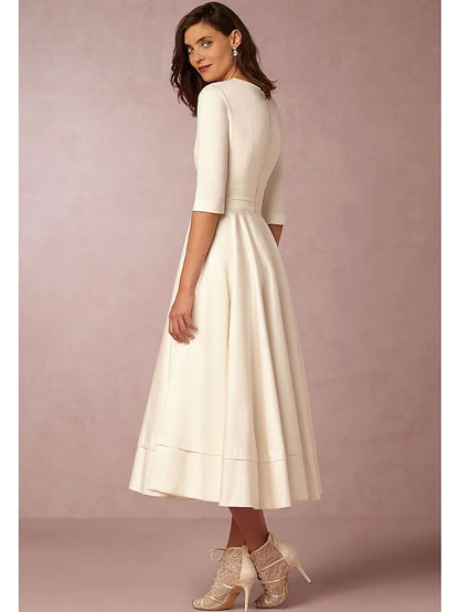 Side view of a woman wearing a dark A-line pleated tea length dress.
