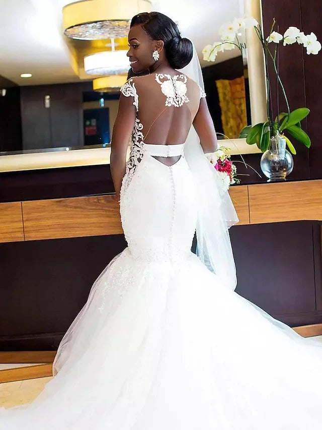 Close-up of the back of the wedding dress, showing lace appliques and open back.