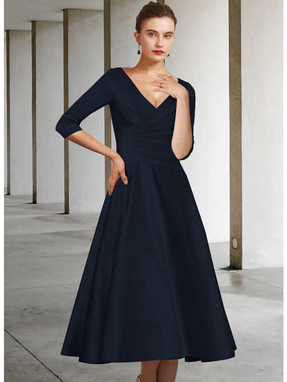Woman wearing a blue A-line V-neck satin tea length Mother of the Bride dress with half sleeves.