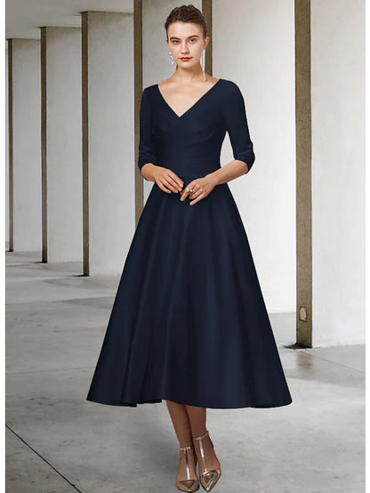 Woman wearing a green A-line V-neck satin tea length Mother of the Bride dress with half sleeves, showing back detail.