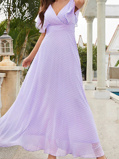 Woman posing in a blue elegant wedding guest dress with a V-neck.