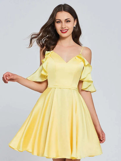 Back view of a model wearing a light pink A-line V-neck sleeveless satin pleated knee-length cocktail dress.