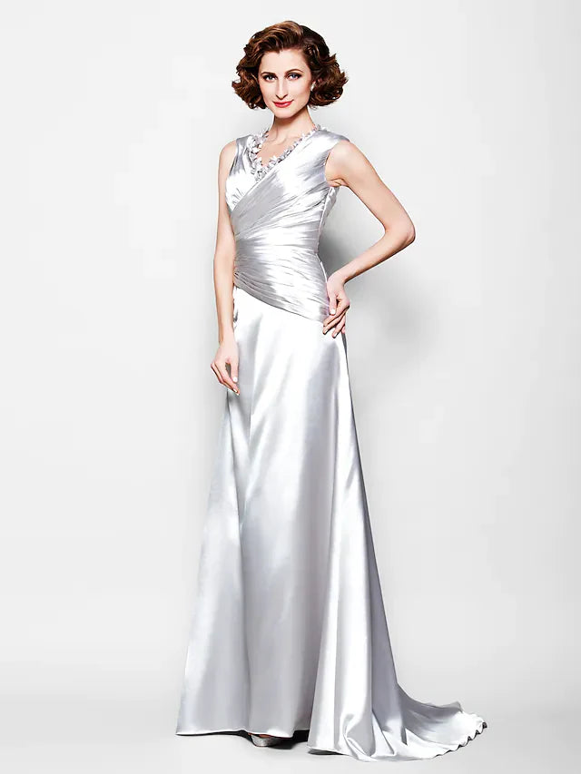 Woman wearing a dark A-line V-neck Mother of the Bride dress with beading and side draping.