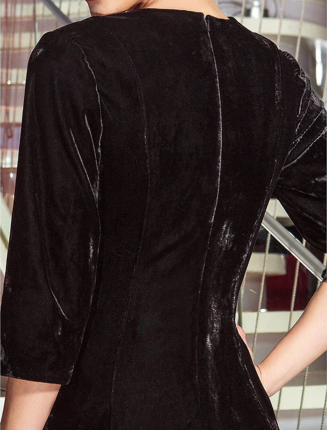 Back view of the floor-length velvet dress, showing the elegant drape and pleats.