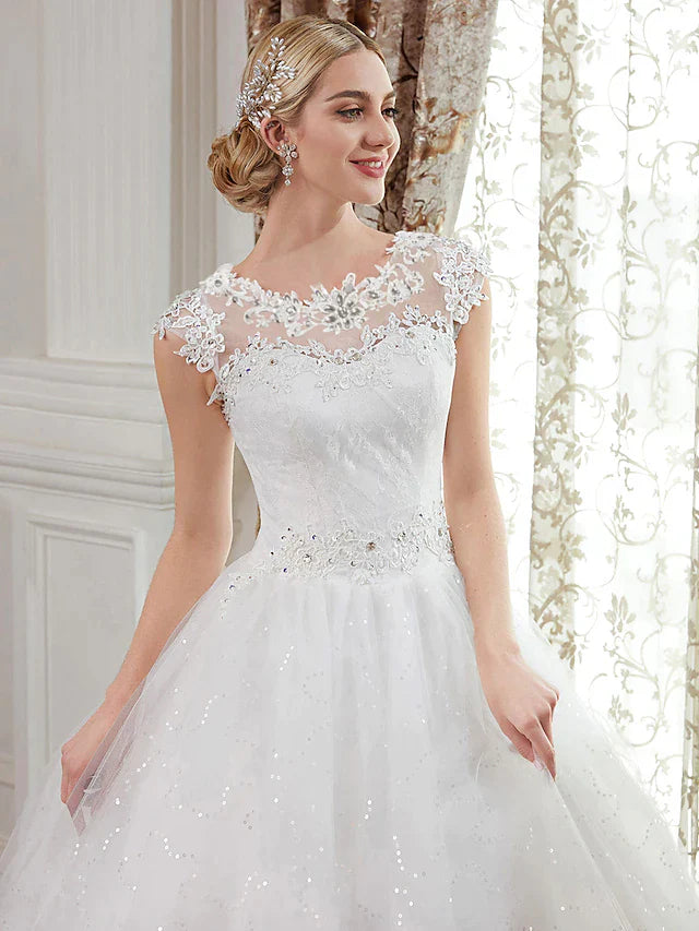 Back view of a floor-length wedding dress showing illusion details and appliques.