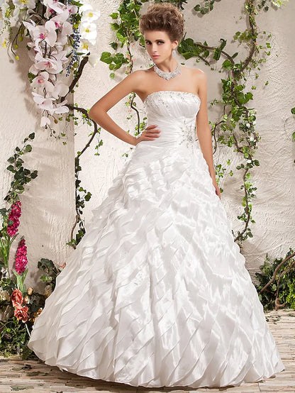 Model wearing a white strapless ball gown wedding dress with beading and ruffles.