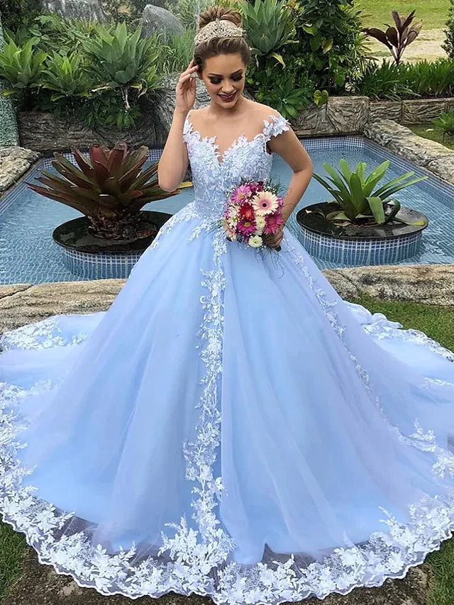 Bride wearing an elegant white ball gown wedding dress with V-neck, cap sleeves, lace, appliques, and a court train.