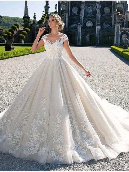 Side view of the ball gown wedding dress, highlighting the flowing chapel train and delicate lace fabric.