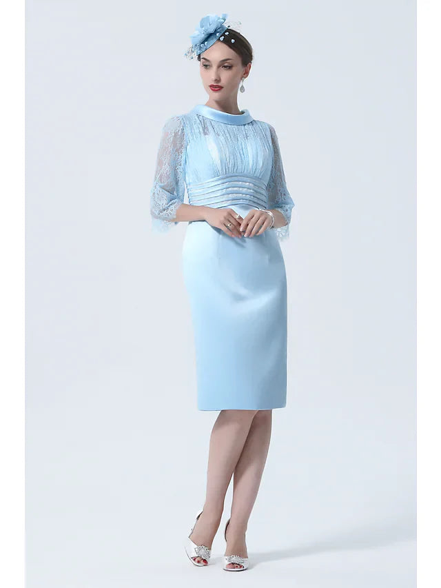 Woman wearing an elegant knee-length charmeuse Mother of the Bride dress with a jewel neck and half sleeves, front view.
