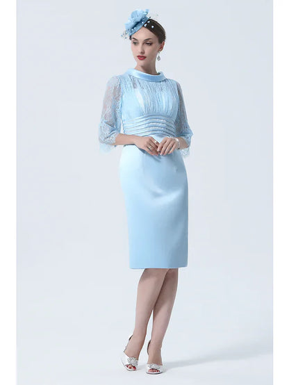 Woman wearing an elegant knee-length charmeuse Mother of the Bride dress with a jewel neck and half sleeves, front view.