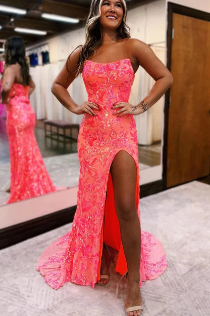 Model wearing a long coral sequin mermaid prom dress with a strapless neckline and high slit.