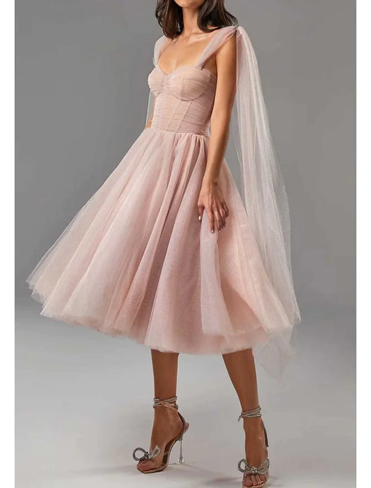 Model wearing a glitter tulle tea-length ball gown with a square neck and corset bodice.