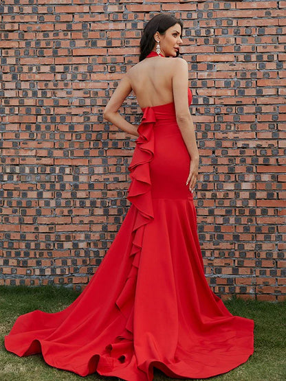 Back view of a red long prom dress with halter neckline and flowing skirt.