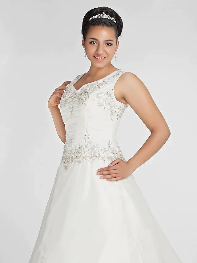 Close-up of the V-neck bodice on the ivory wedding dress, featuring delicate beading and lace embroidery.