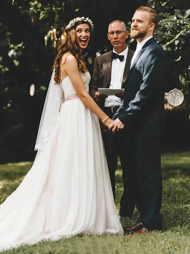 Model wearing an elegant lace tulle spaghetti strap wedding gown with a court train.