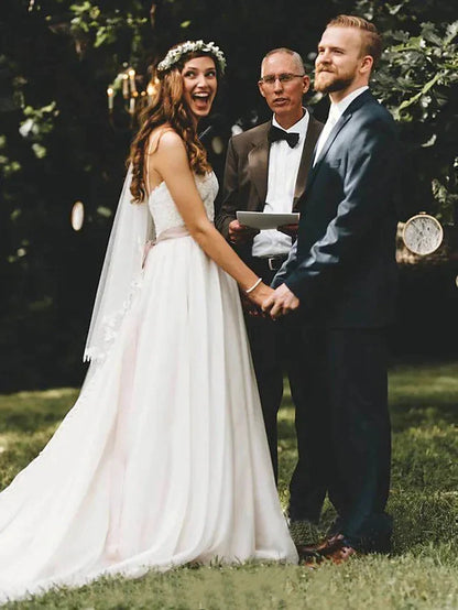 Model wearing an elegant lace tulle spaghetti strap wedding gown with a court train.
