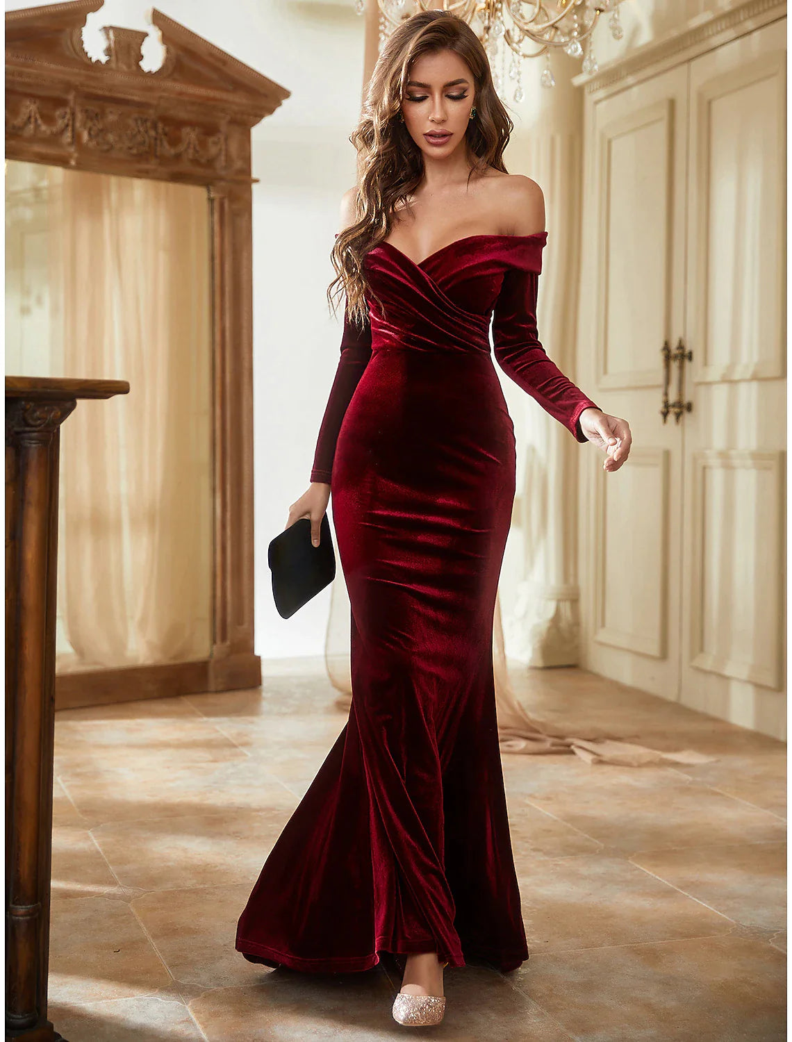 Side view of a long sleeve off-shoulder velvet formal dress with a trumpet silhouette.