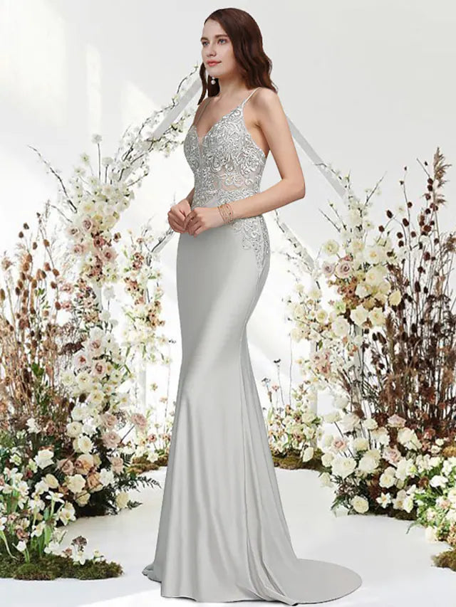 Woman wearing a navy blue mermaid trumpet evening gown with V-neck and appliques.