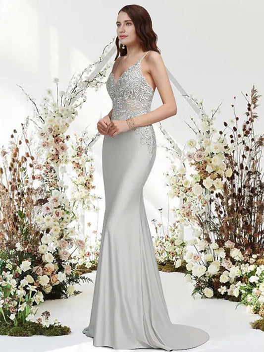 Woman wearing a navy blue mermaid trumpet evening gown with V-neck and appliques.