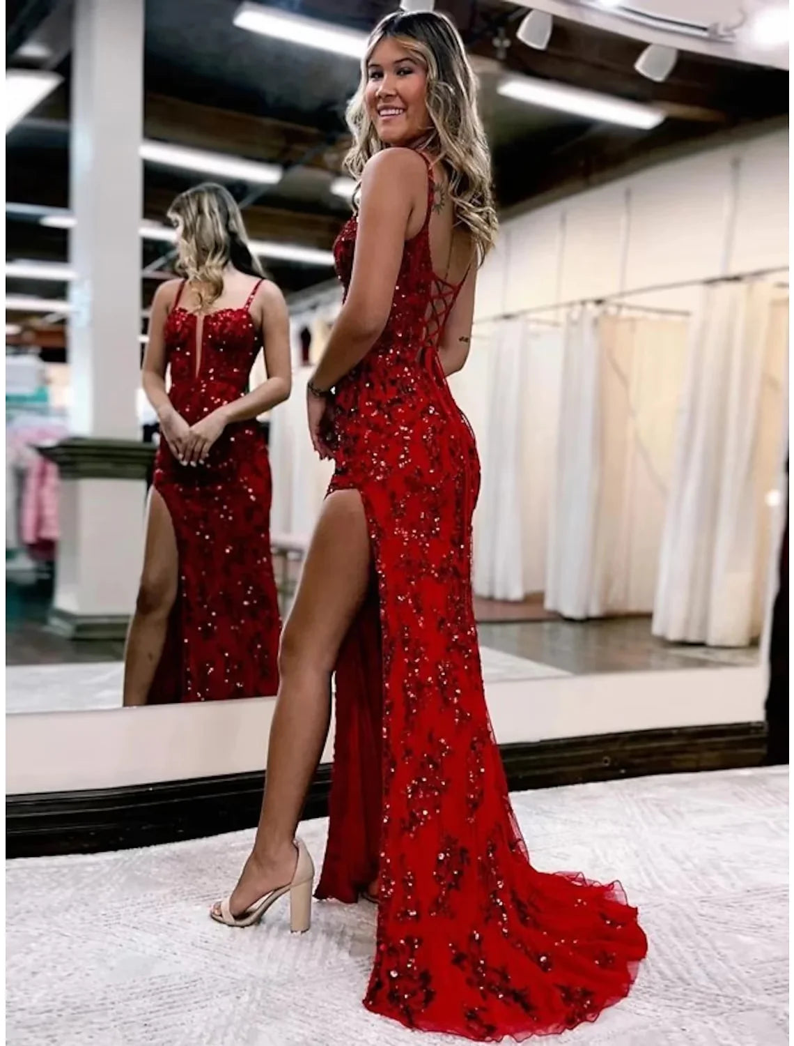 Side view of a woman wearing a white mermaid trumpet evening gown with appliques.