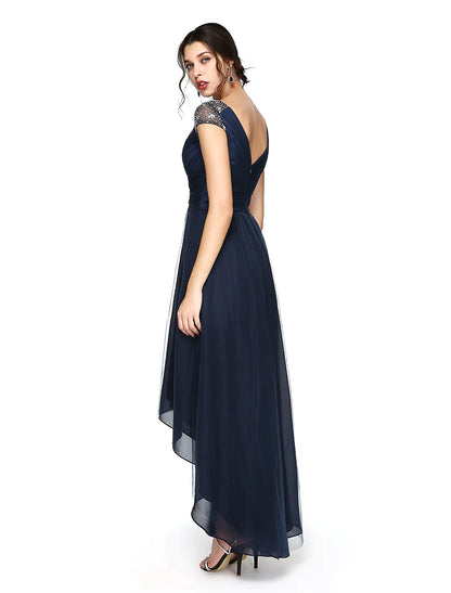 Side view of a model in a light-colored sheath column dress, highlighting the asymmetrical short sleeve.