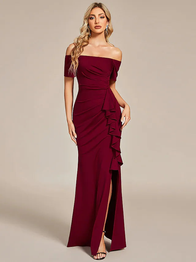 Woman in elegant black off-shoulder ruched long dress, side view.